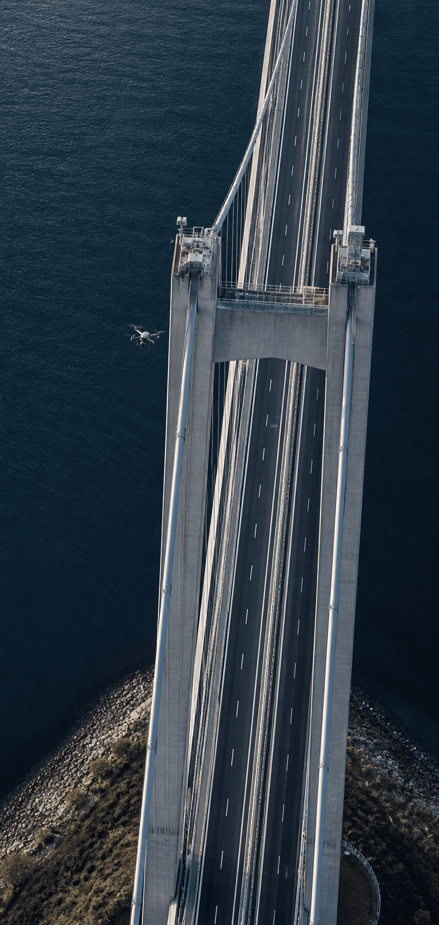 Professional inspection drone flying beside a bridge tower